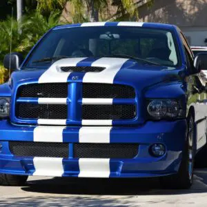 A blue truck with white stripes on it's hood.