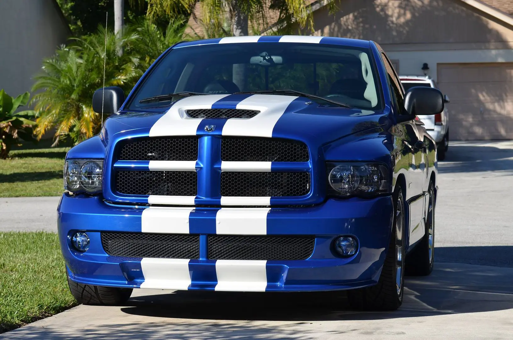 A blue truck with white stripes on it's hood.