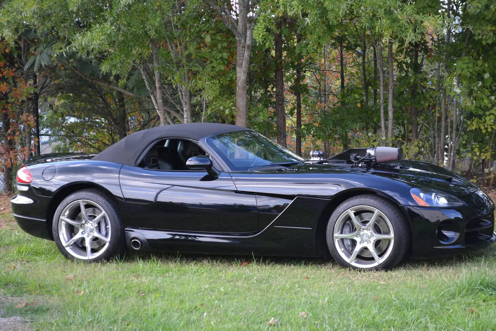 A black sports car parked in the grass.