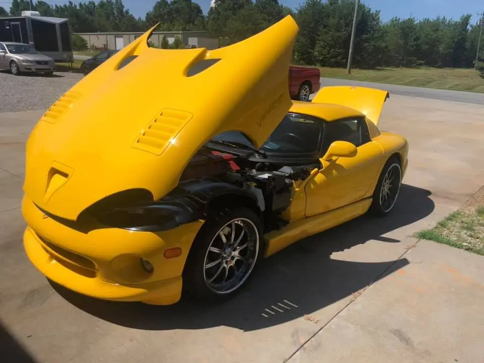 A yellow sports car with its hood open.