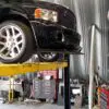 A car is on the top of a lift in an auto shop.
