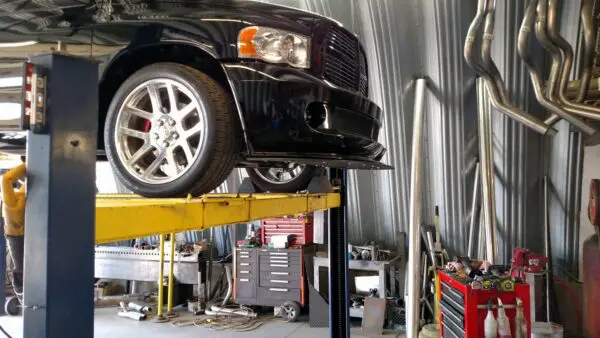 A car is on the top of a lift in an auto shop.