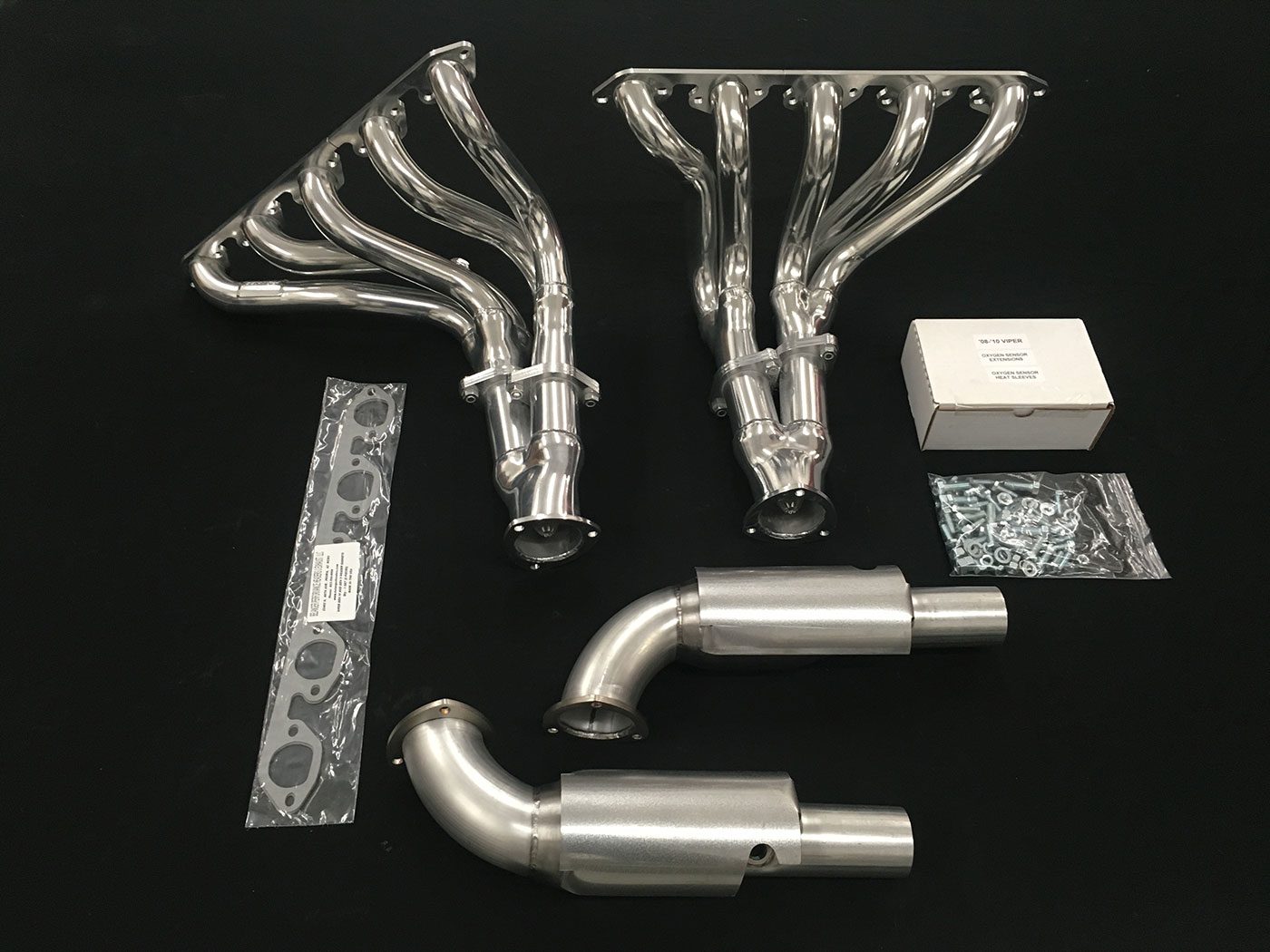 A set of exhaust pipes and headers are laid out on the table.