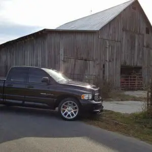 A truck parked in front of a barn.