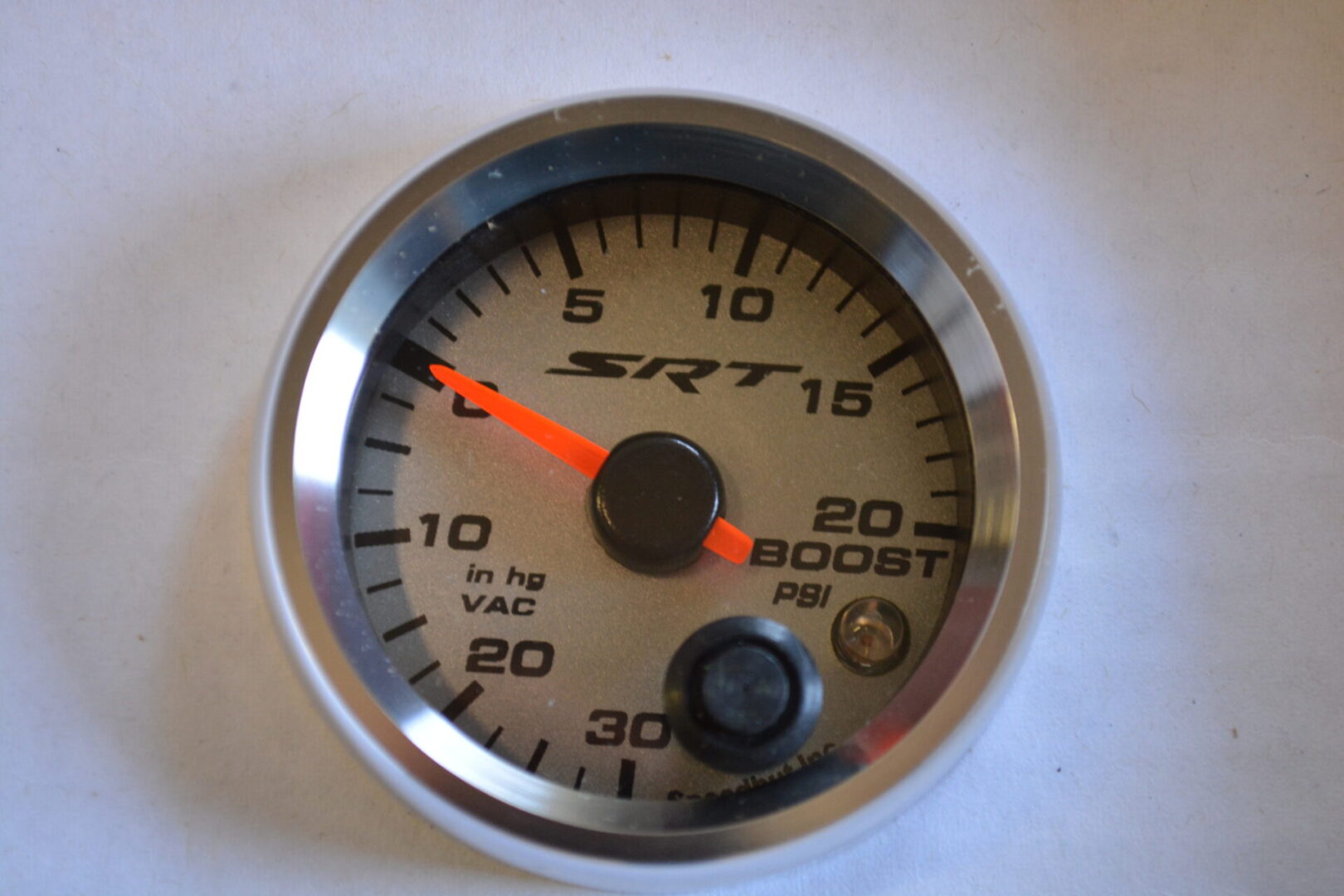 A white and silver gauge with orange needle.