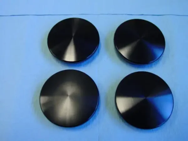 A group of four black discs sitting on top of a table.