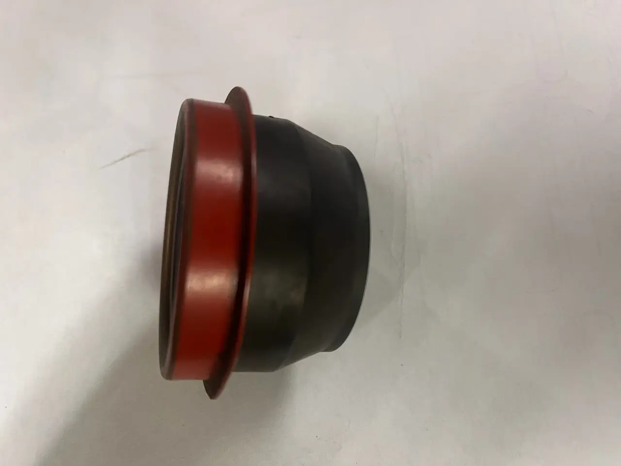 A black and red rubber cap sitting on top of a white surface.