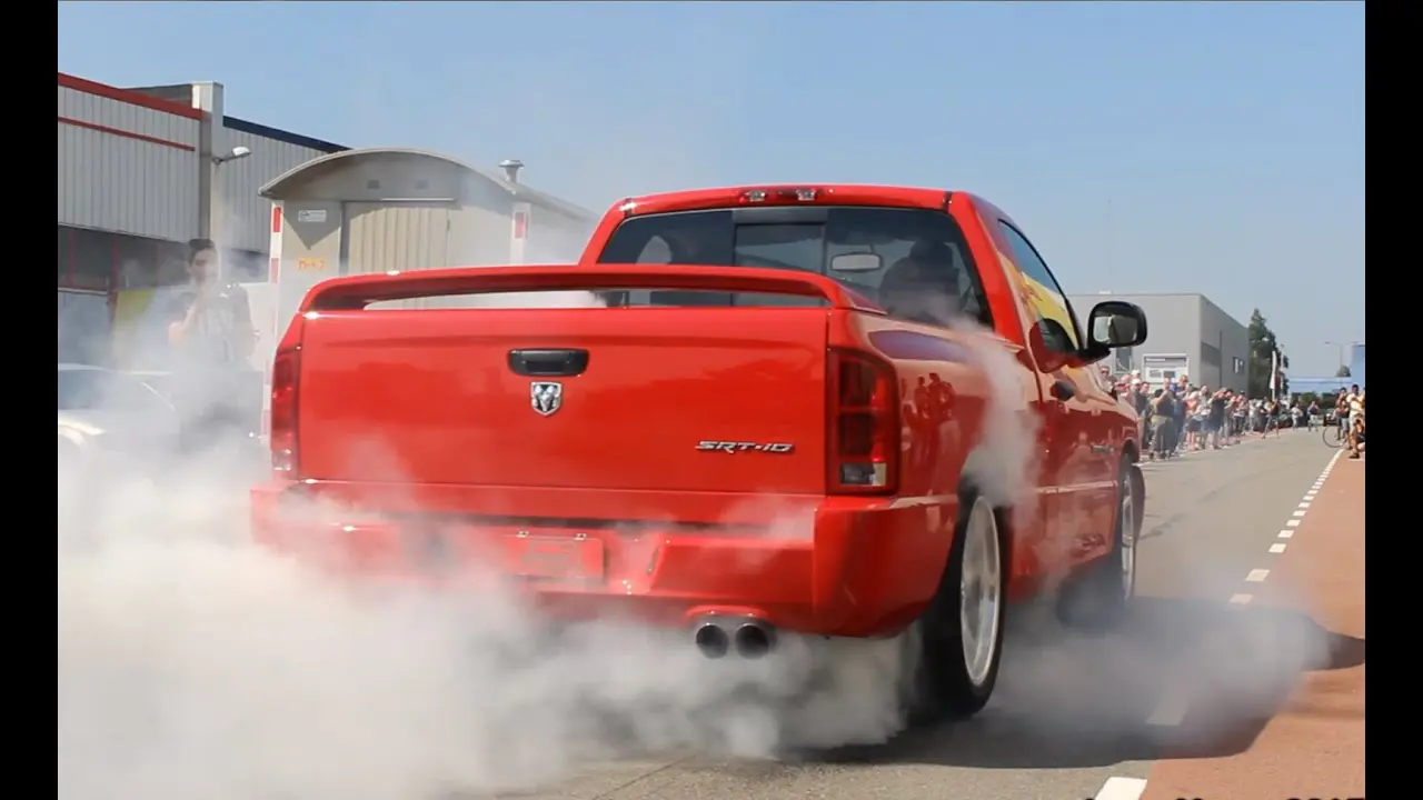 A red truck with its trunk open is smoking.